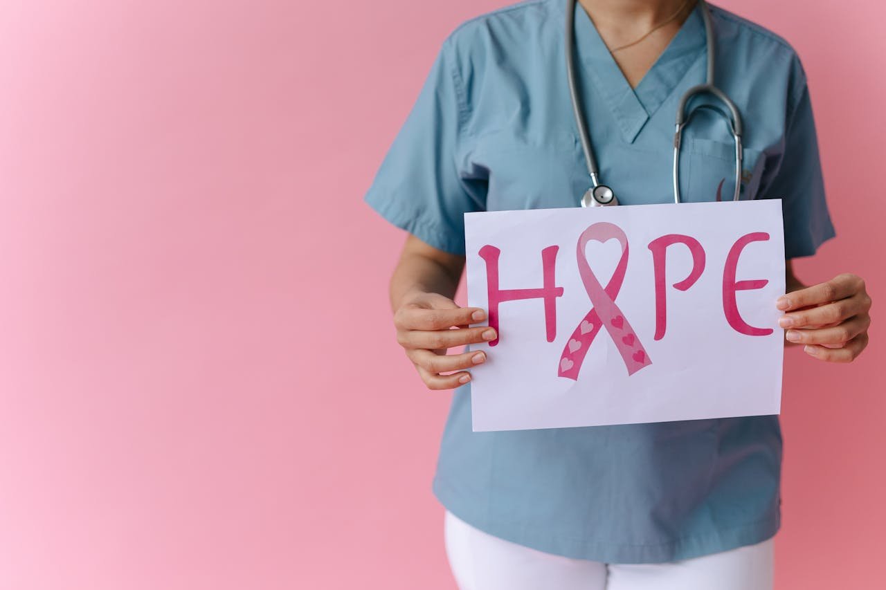 Doctor holding a 'Hope' sign advocating breast cancer awareness with a pink background.